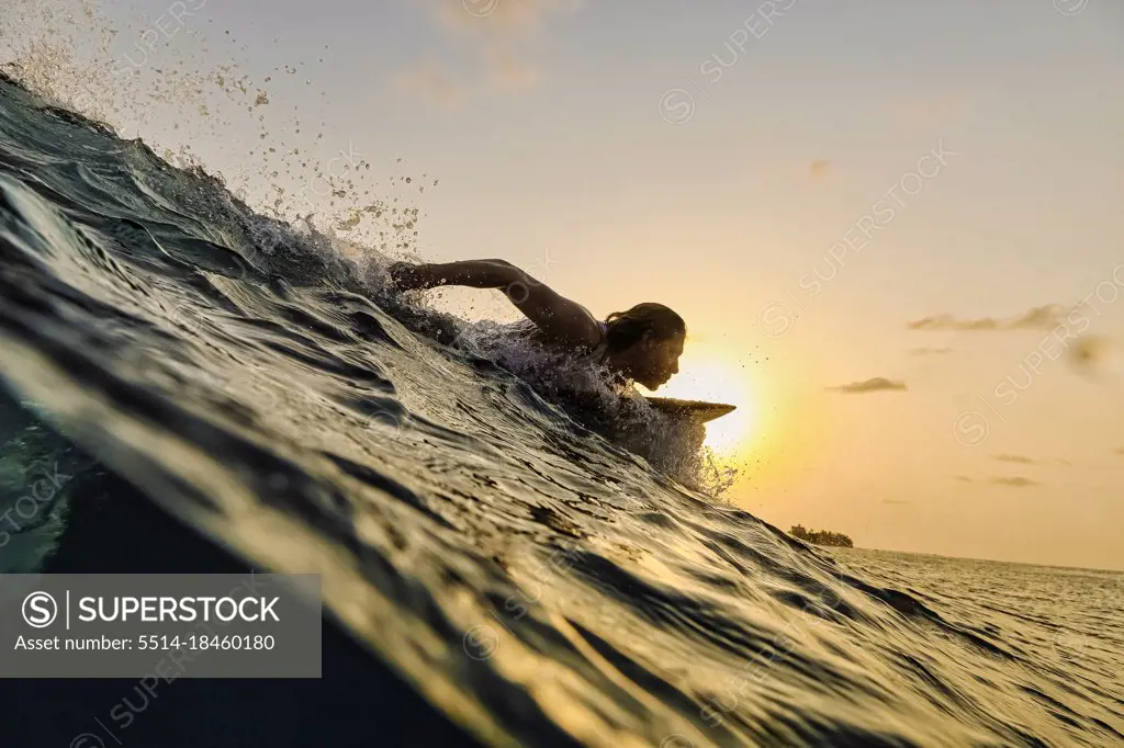 Male surfer in ocean at sunset time