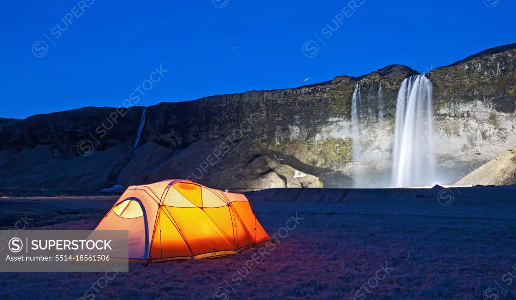 lit up tent at the waterfall Seljalandsfoss in south Iceland
