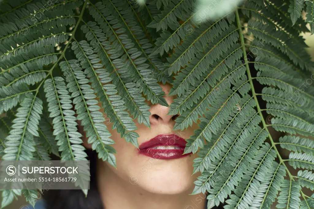 Sexy portrait of woman with tree leaves on top of her face.
