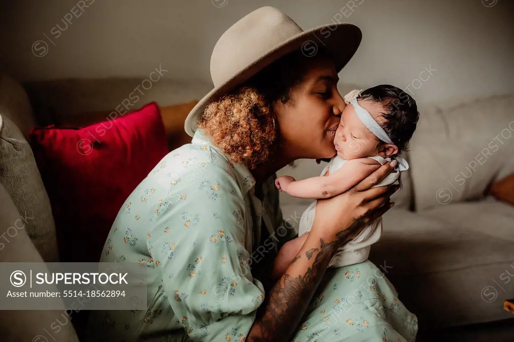 Black mother kissing her daughter on the couch.