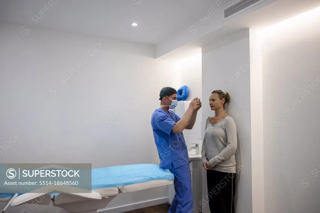 Aesthetic surgeon taking photograph of patient before operation