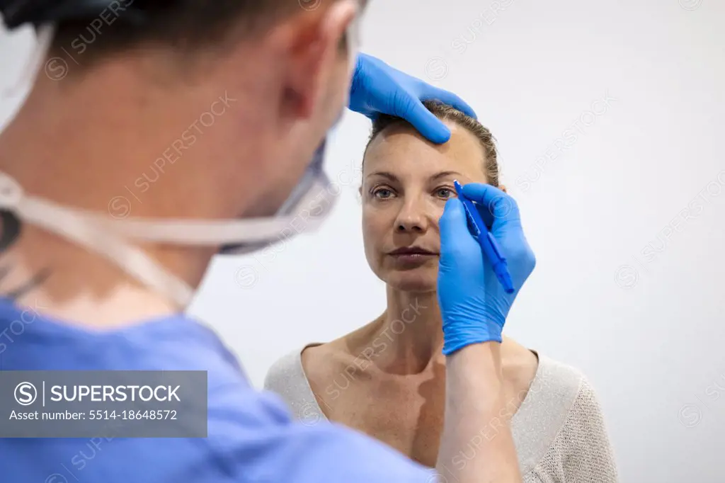 Surgeon drawing line on girl eye with marker preparing for procedure.