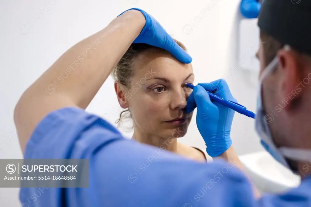 Surgeon drawing line on girl eye with marker preparing for procedure.