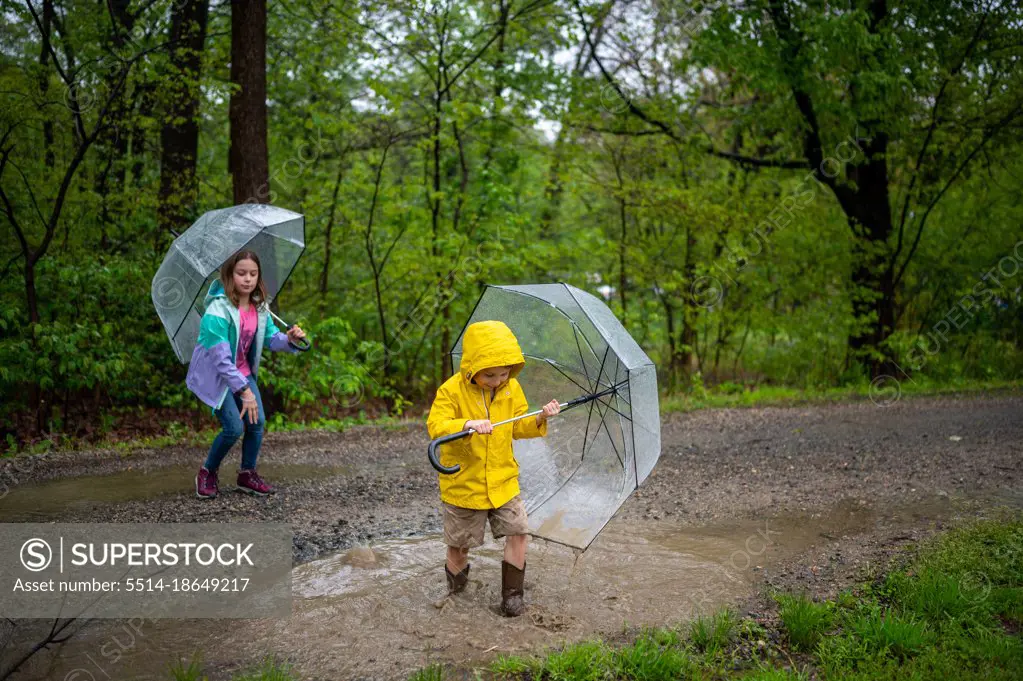 Boy and girl playing in the rain with umbrellas