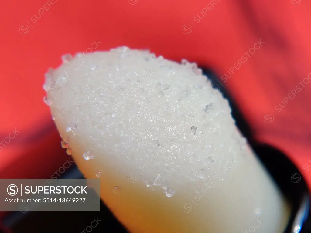 Macro photo of white sugar lip scrub on red background