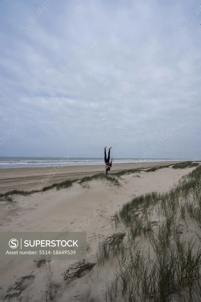 A man doing a Handstand on a beach near the sea, Netherlands, Europe