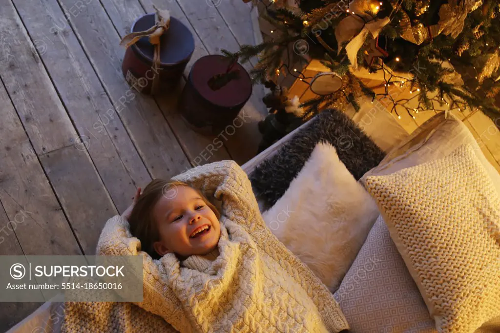 Smiling child lies on the bed near the Christmas tree top view.