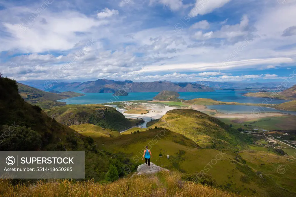 Girl On Cliff Overlooking Lush Ocean Viewpoint In Wanaka New Zealand