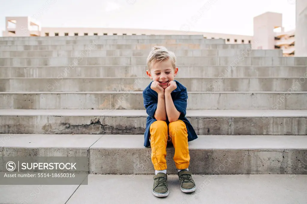 Portrait of young boy laughing on concrete steps in Downtown Phoenix