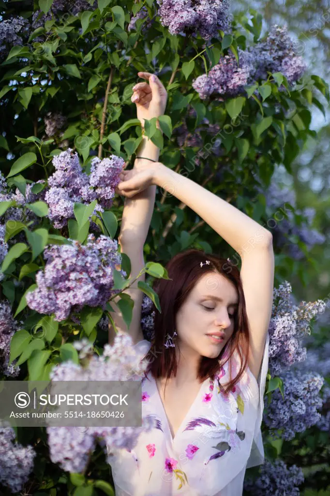 Red hair woman near lilac bush bloom