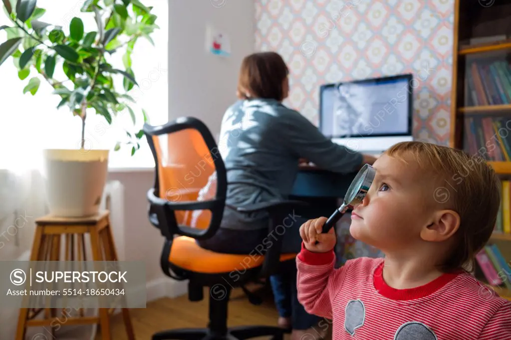 woman working at the computer while the child is exploring the room