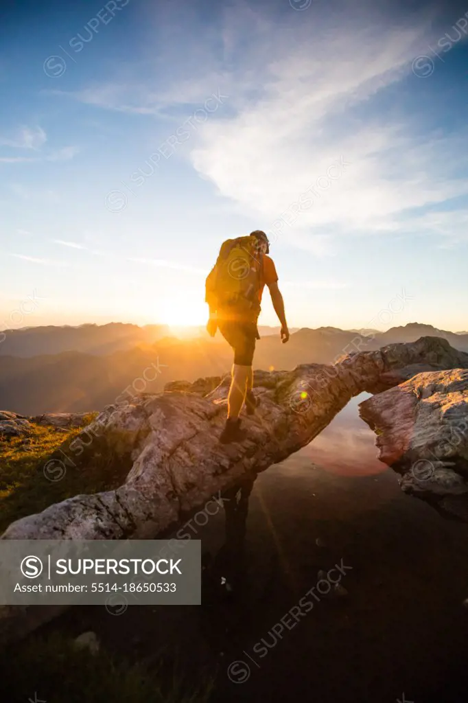 Rear view of backpacker hiking on mountain during sunset.