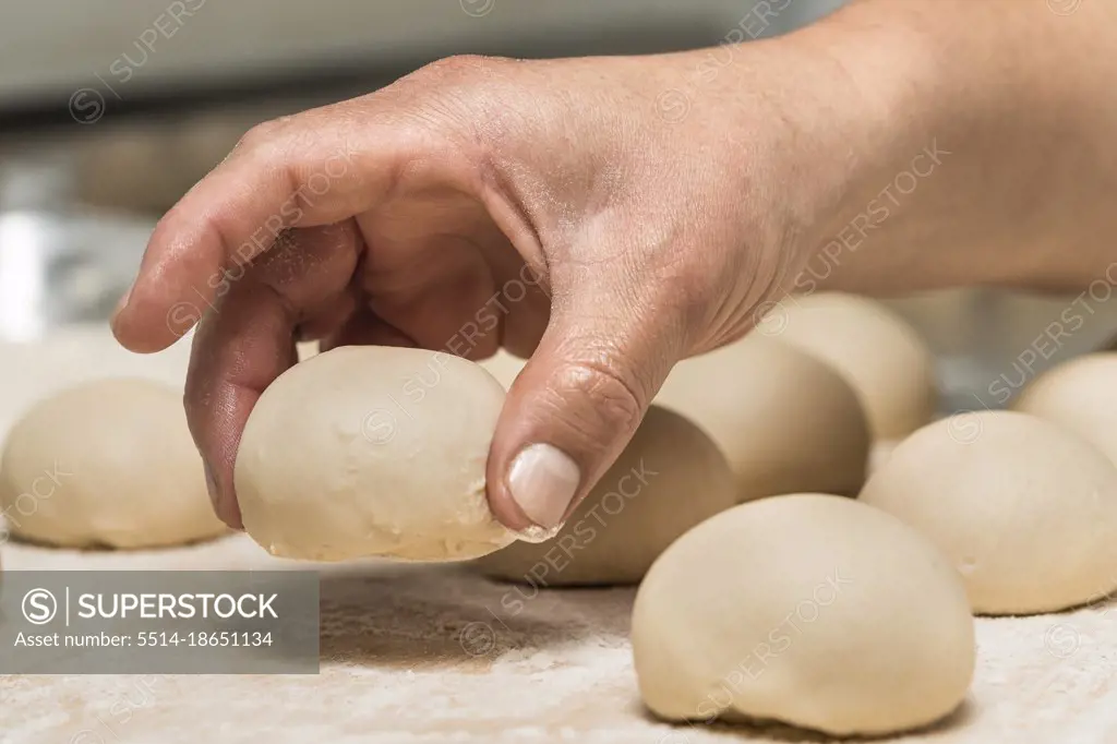 Man picking up a uncooked bun from a metal table in an artisan bakery