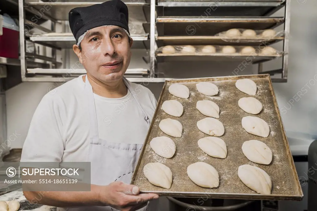 Artisan baker showing a plate with pieces of uncooked bread