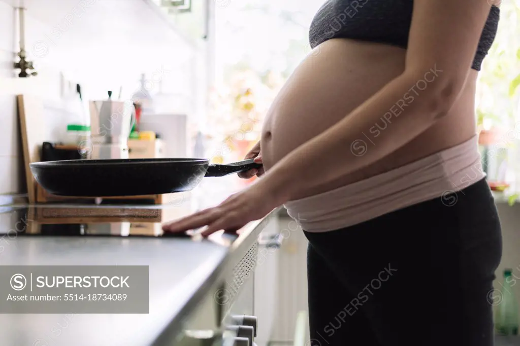 Pregnant woman cooking in the kitchen of her home.