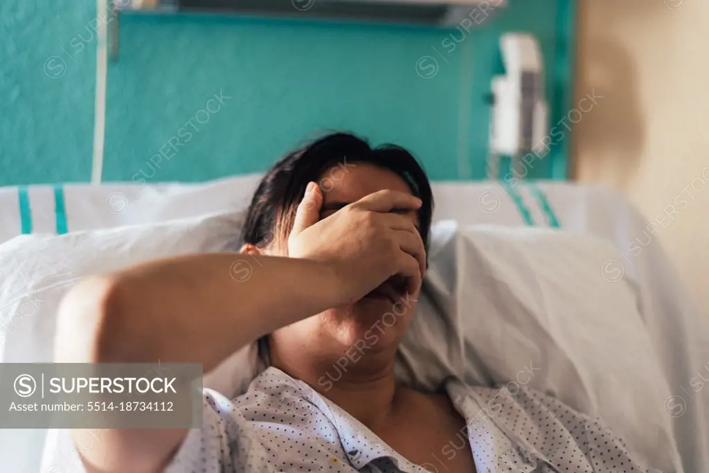 Young woman hospitalized in a bed. Gestures of pain and concern.
