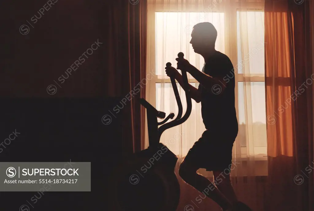 A man goes in for sports at dawn at home, silhouette