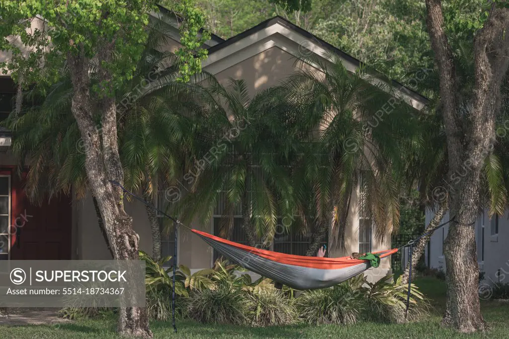 Male college student checks phone in front yard hammock