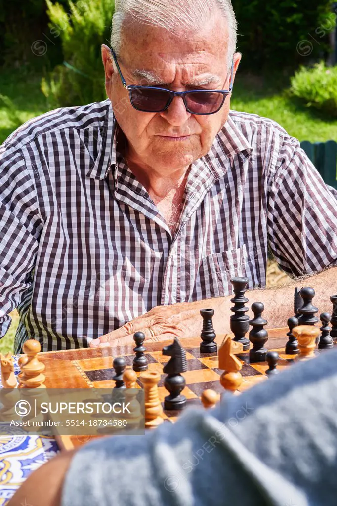 Senior man playing chess in home garden