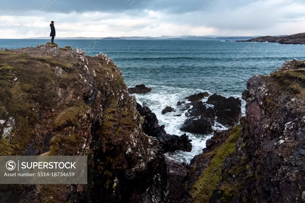 Solo woman standing on cliff above ocean