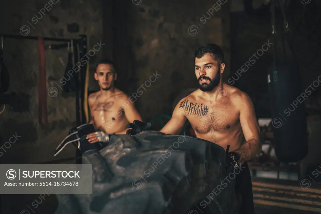 Two friends doing a training with a tractor wheel