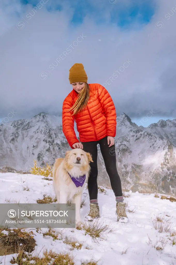Female Hiker and Fluffy Dog on A Snowy Mountain Ridge