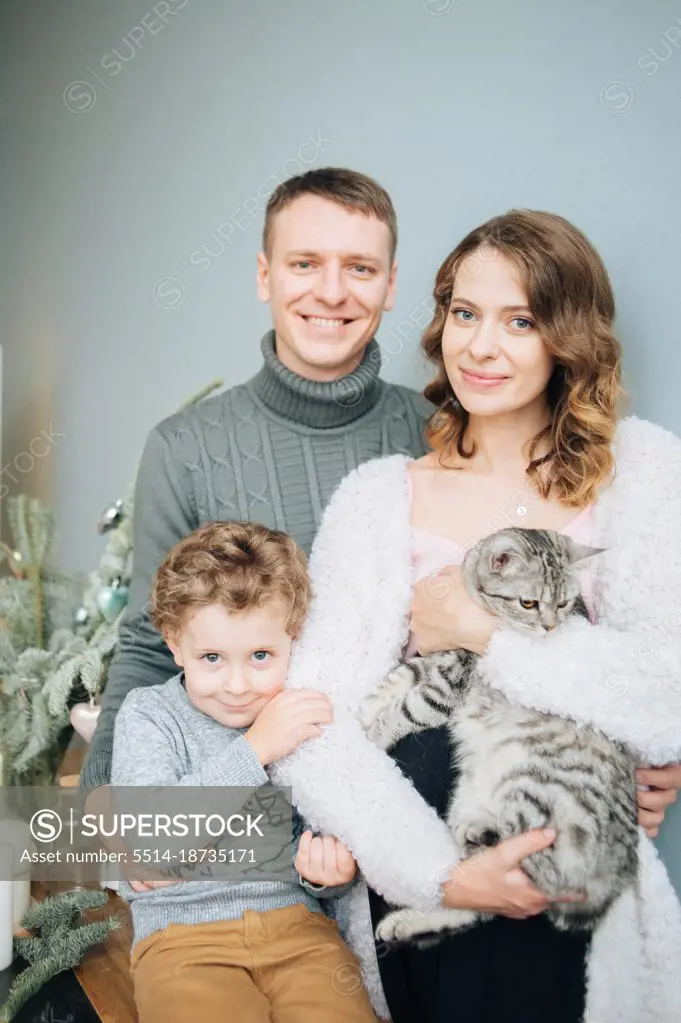Family of three with cat look at a camera with smiles.