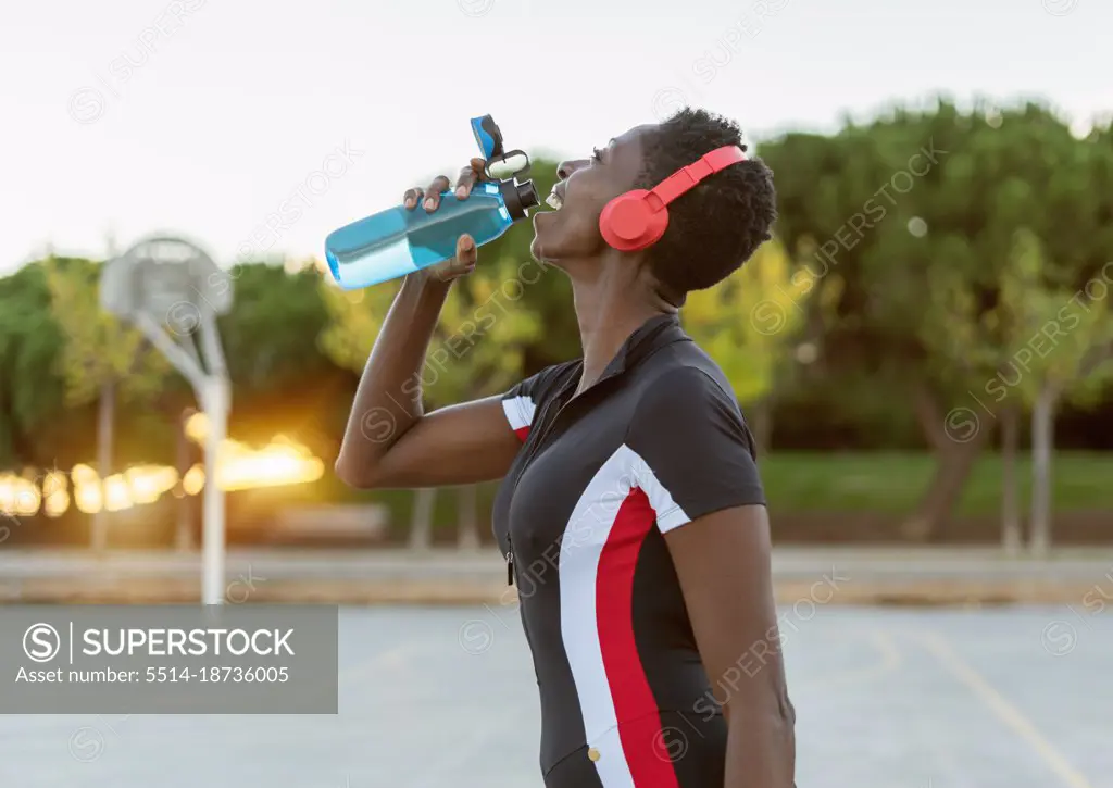 Fitness woman relaxing, drinking water after training workout