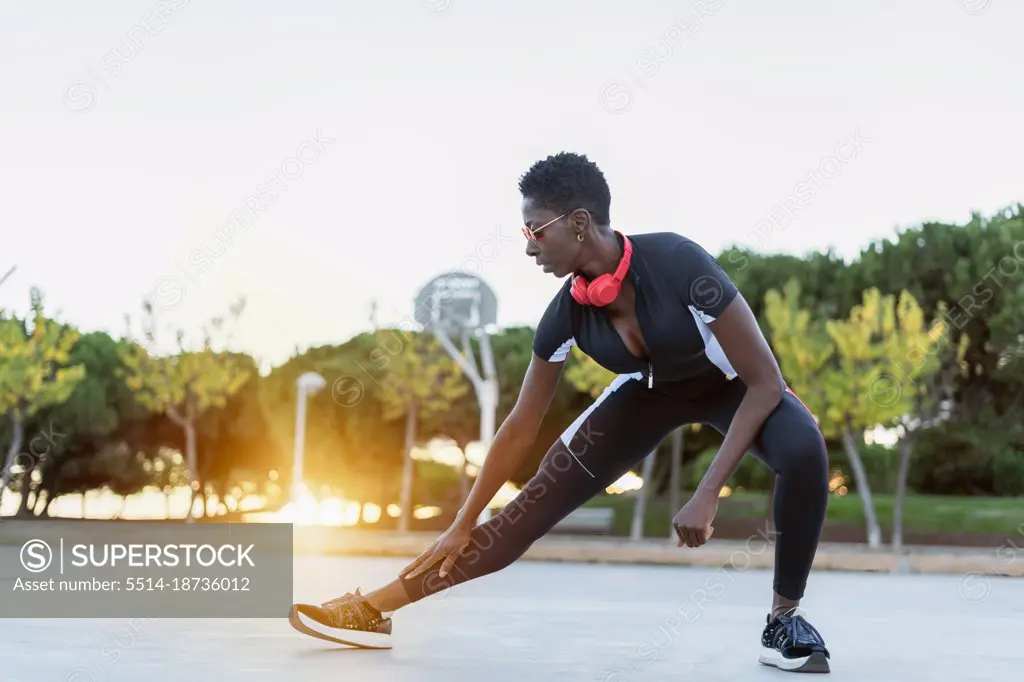 Athletic afro female stretching and warming up before training outdoor