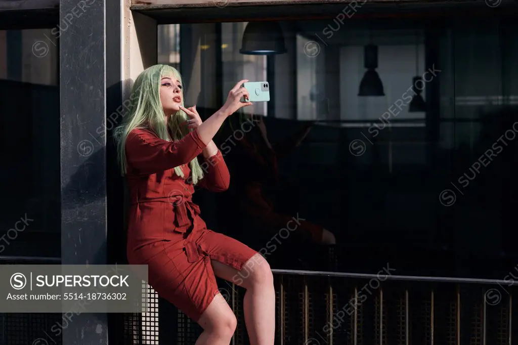 Alternative woman with green hair takes a selfie with her phone