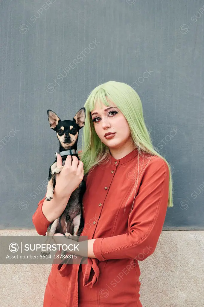 Alternative woman with green hair poses with her dog looking at camera