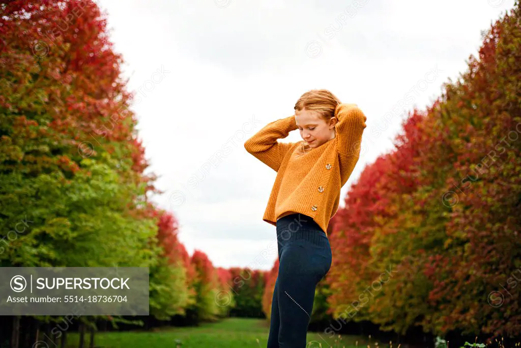 Happy tween girl surrounded by fall color trees.