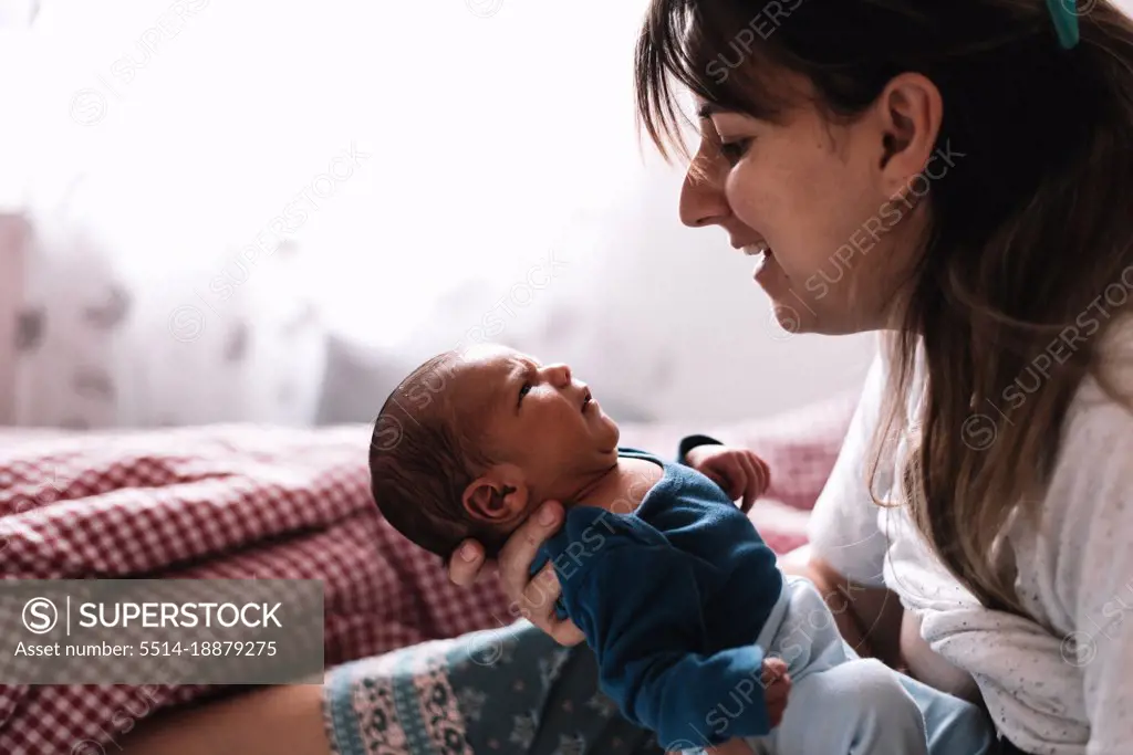 Mother gesturing and talking to her newborn baby.