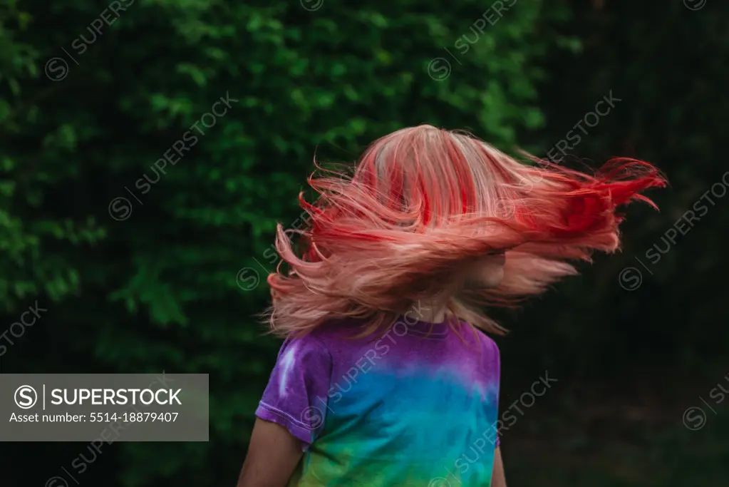 Young girl shaking hair outside with dyed red hair