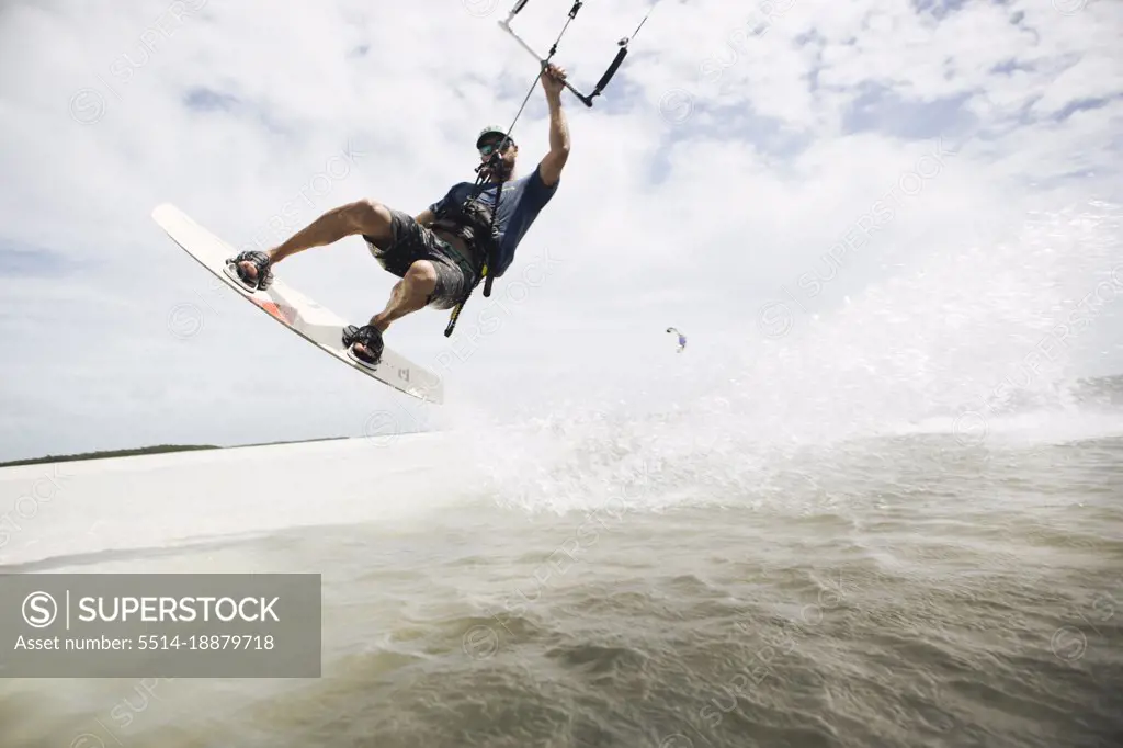 A man kiteboarding in the florida keys jumps out of the water