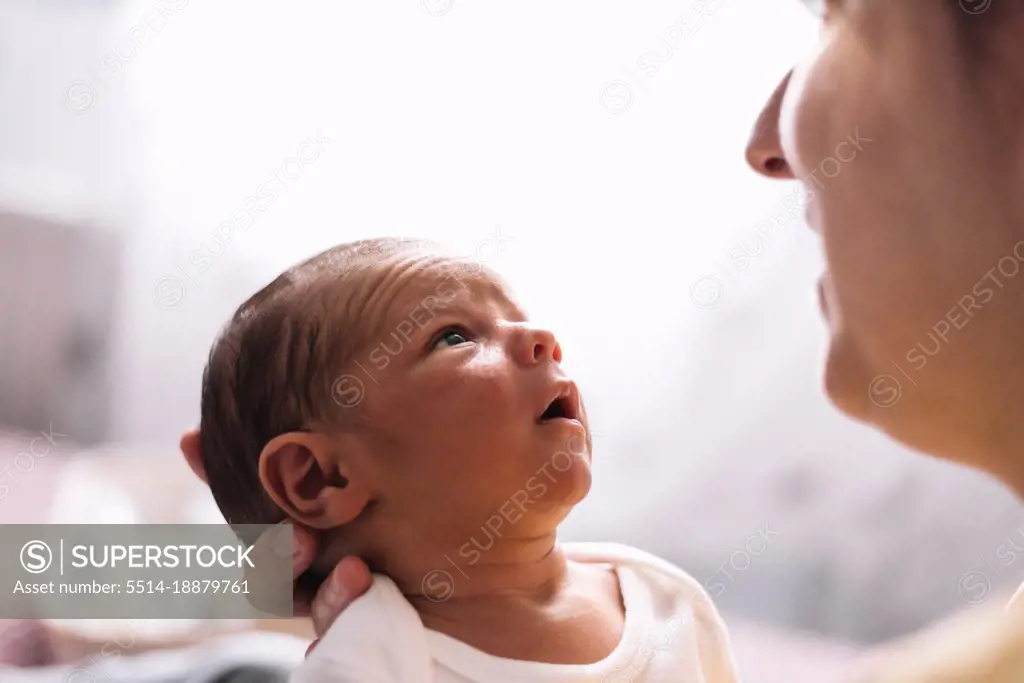 Portrait of serious newborn baby looking at his mother.