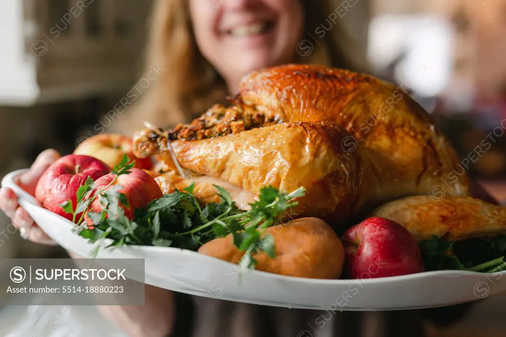Close up of fried turkey being presented on a platter with apples