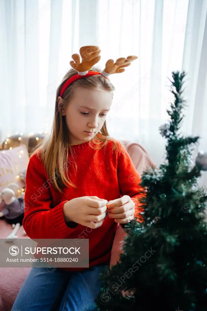 girl in a christmas costume decorates the christmas tree