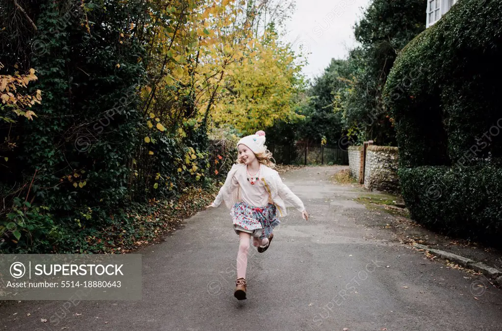 girl running through the streets joyfully in Autumn Uk