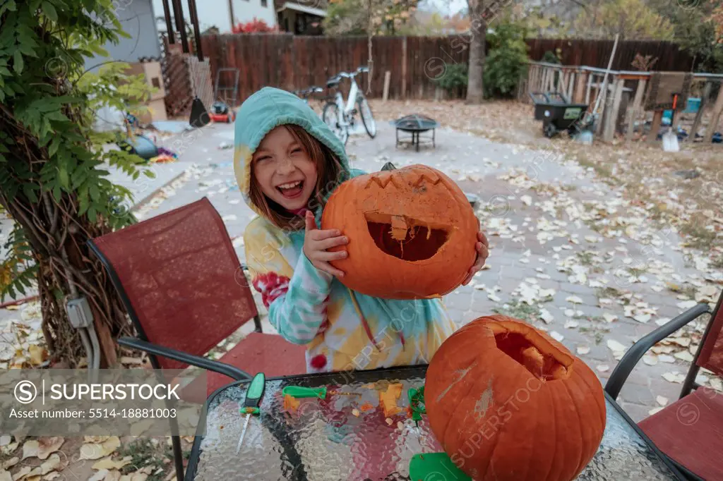 Happy young girl showing off her carved pumpkin