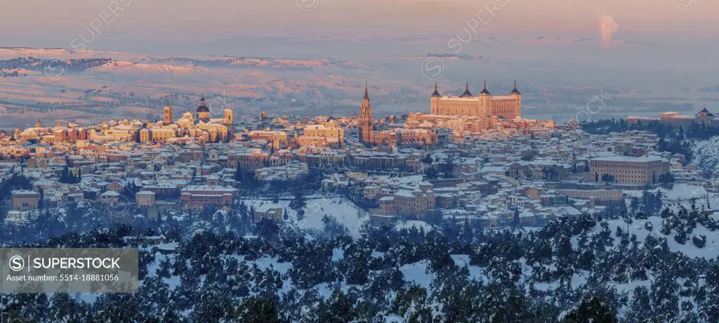 Snowy old town with castle on hill with golden colors at sunset