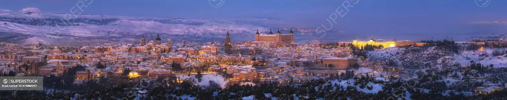Snowy old town with castle on hill at sunset and illuminated streets