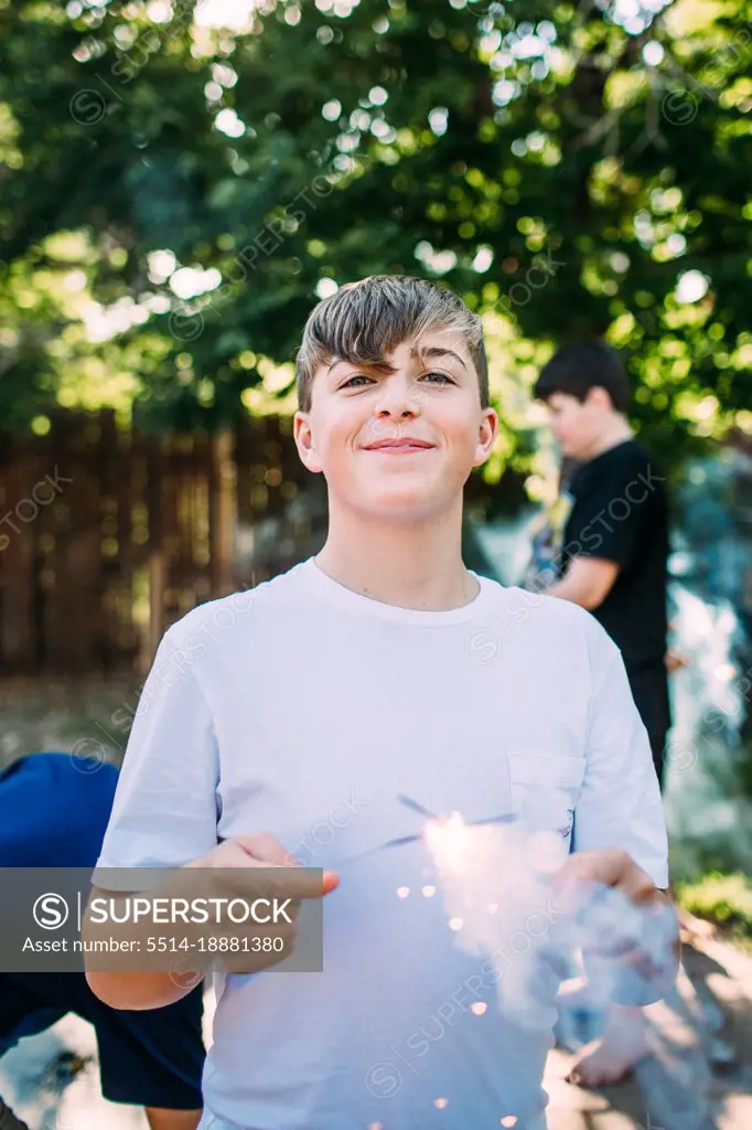 Happy teen boy playing with a sparkler outside