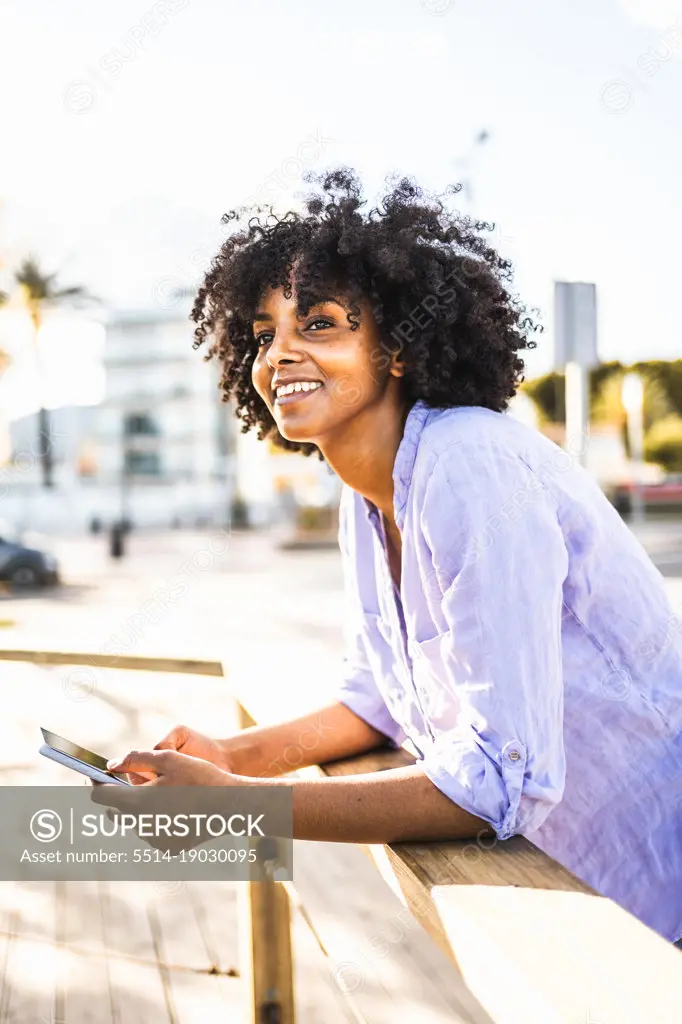 Beautiful young black woman happy while using her smartphone
