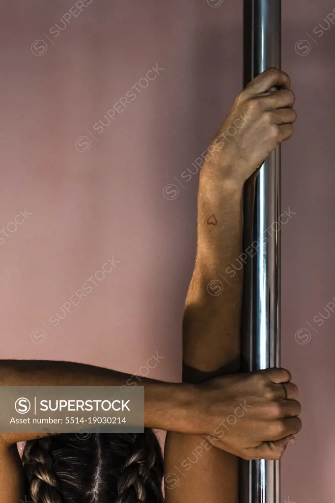 Detail of female athlete's hands holding pole in pole dance studio