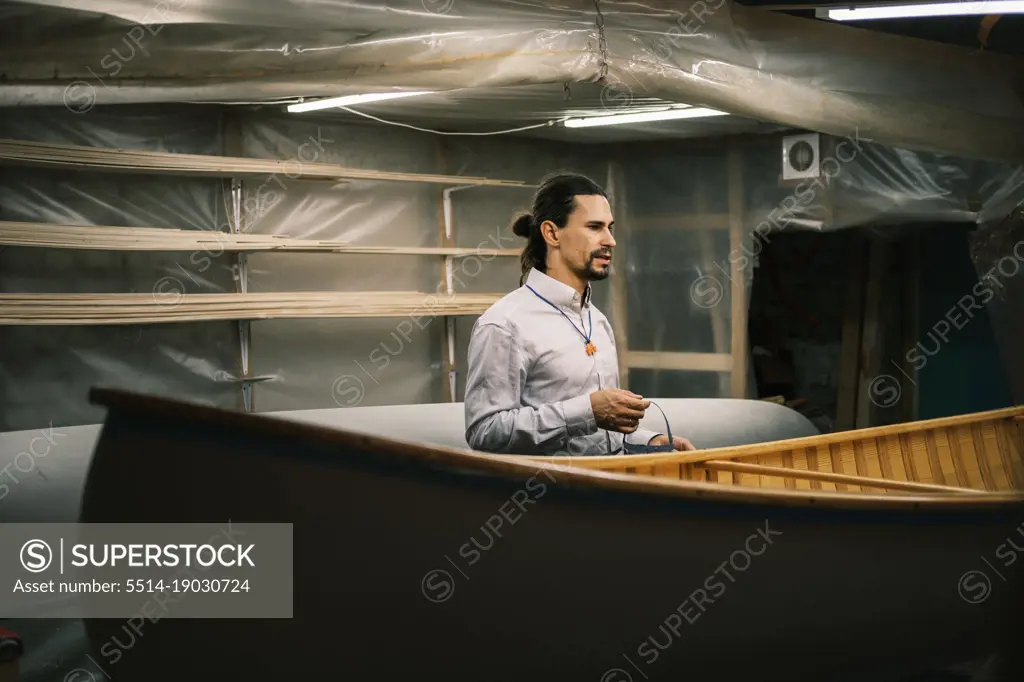 Canoe builder at workshop next to the boat, small business and craft