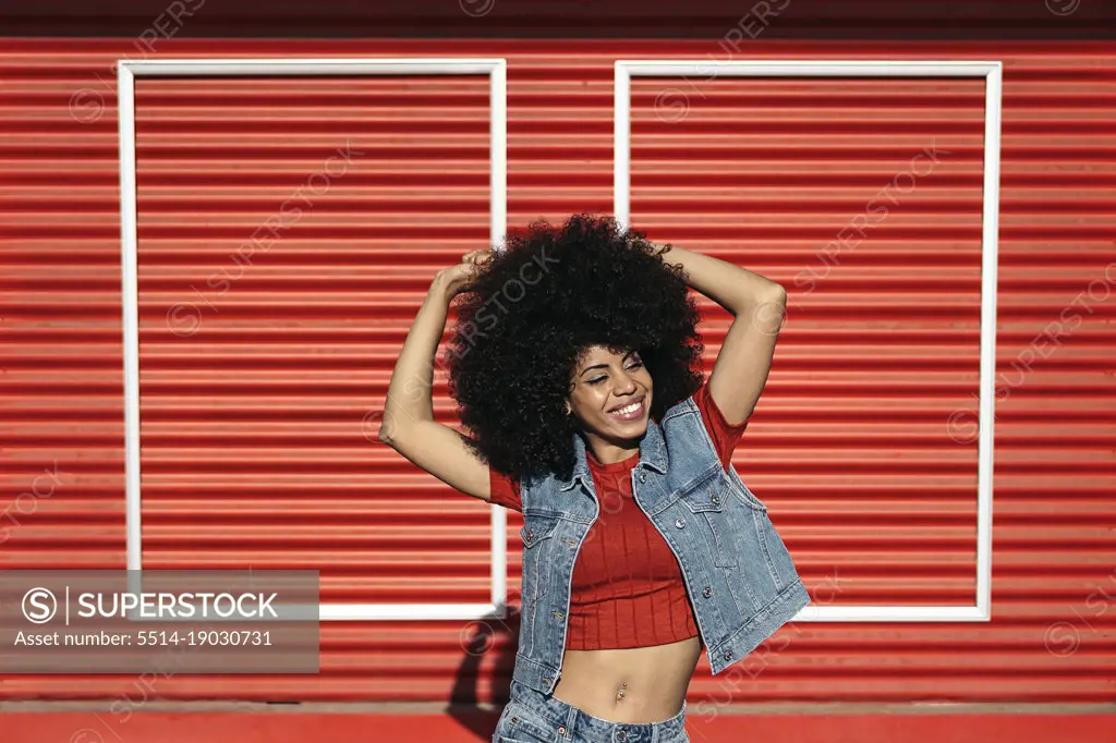 Young afro woman posing over a red background