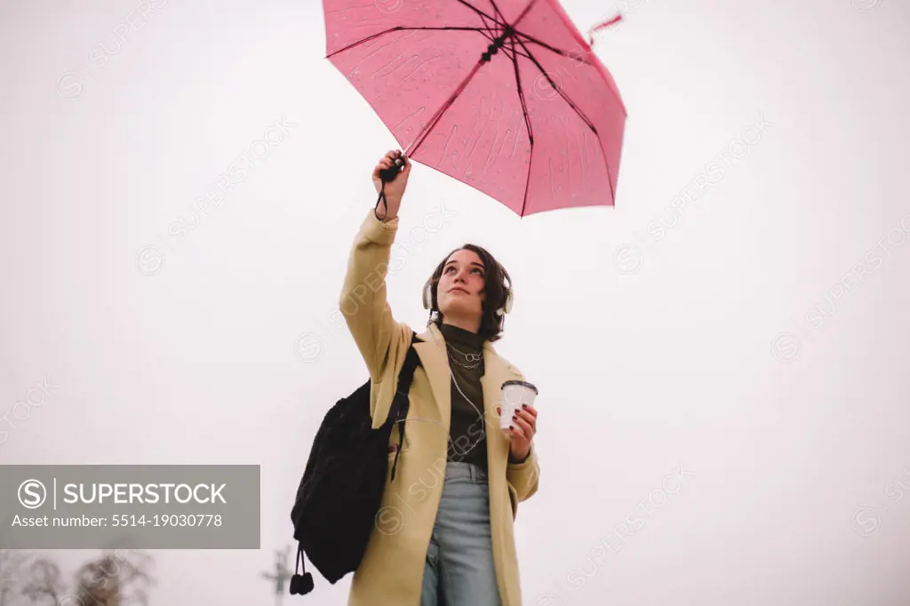 Teenage girl with an umbrella walking in city in autumn