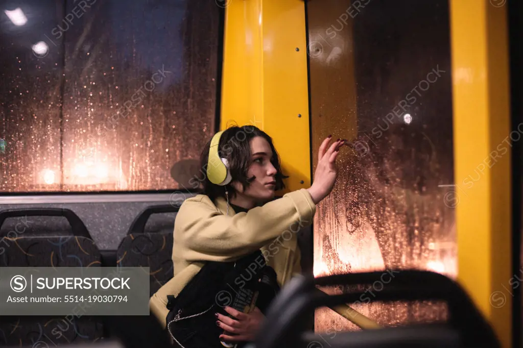 Young woman drawing on window while traveling in trolley bus
