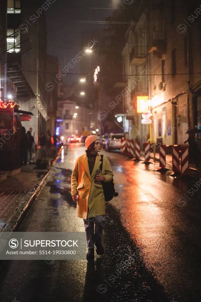 Young woman walking on street in city at night